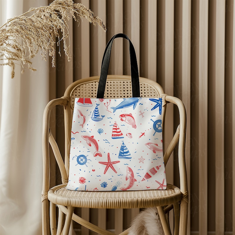 May include: A white tote bag with a nautical theme. The bag features red and blue illustrations of sailboats, fish, starfish, and seashells. The bag has black handles.