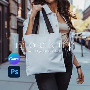 Può includere: Una borsa tote bianca con manici neri. La borsa ha il testo "mockup" e "Smart Object PSD + PNG" stampato su di essa.