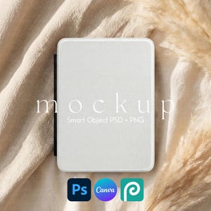 May include: A white rectangular mockup with the word "mockup" in a delicate font. Below the word "mockup" is the text "Smart Object PSD + PNG". The mockup is on a beige fabric surface, with a few sprigs of dried grass in the background. The image also includes the logos for Photoshop, Canva, and Placeit.