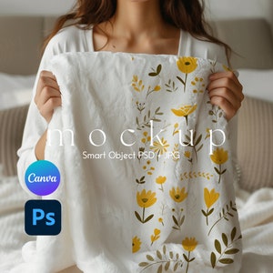 May include: A white plush blanket with a floral pattern featuring yellow flowers and green leaves. The blanket is being held by a person. The text "mockup" and "Smart Object PSD + JPG" is printed on the blanket.
