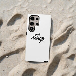 May include: White phone case with a black outline and a camera lens cutout. The case has the text "your design here" printed on it.