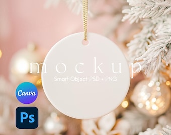 May include: White ceramic ornament hanging on a snowy Christmas tree branch. The ornament is blank and ready for customization. The text "Mockup Smart Object PSD + PNG" is printed on the ornament.