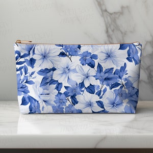 May include: A white zippered pouch with a blue floral pattern. The pouch is made of fabric and has a zipper closure.