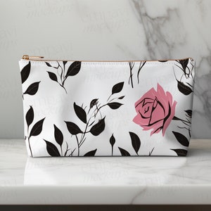 May include: A white zippered pouch with a black and pink floral pattern. The pattern features black leaves and stems with pink roses.