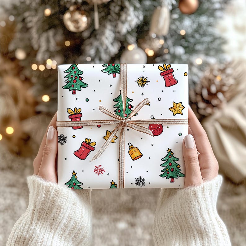 May include: A square gift box wrapped in white paper featuring a colorful pattern of green Christmas trees, red gift boxes, yellow stars, gold bells, and black snowflakes, tied with a thin, light brown ribbon centered in a cross pattern.