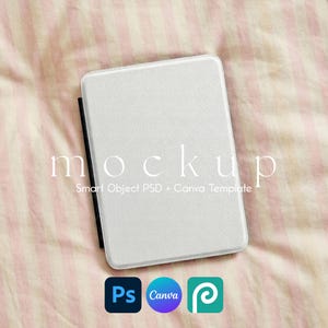 May include: A white rectangular object with rounded corners, possibly an e-reader or tablet, lies on a pink and white striped fabric. The word "mockup" is printed on the fabric. Below are the logos for Photoshop, Canva, and a third app.