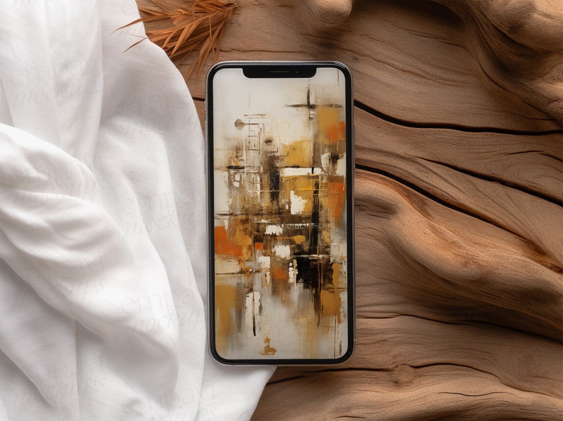 Blank black smartphone on natural wood with soft white fabric and dried leaves, creating a warm, organic setting for mobile design presentations