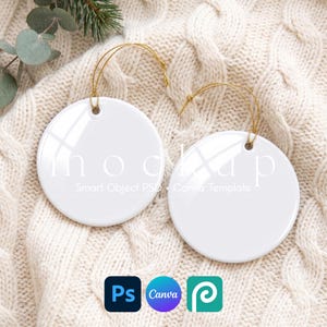 May include: Two blank white circular ceramic ornaments with gold hanging strings. The ornaments feature the text mockup Smart Object PSD + Canva Template. The image includes icons for Photoshop, Canva, and a third design software application.