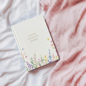 May include: A white hardback journal featuring a floral illustration along the bottom edge with various colourful wildflowers and greenery. The text "YOUR DESIGN HERE" is printed in dark lettering on the centre of the front cover.