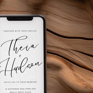Blank black smartphone on natural wood with soft white fabric and dried leaves, creating a warm, organic setting for mobile design presentations