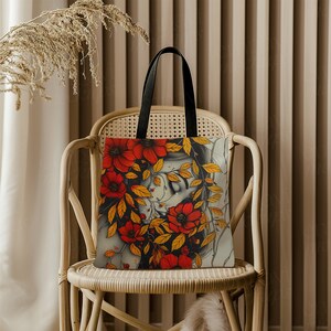 May include: A tote bag with a colorful floral design featuring a woman's face partially obscured by the flowers. The flowers are red, orange, and yellow.