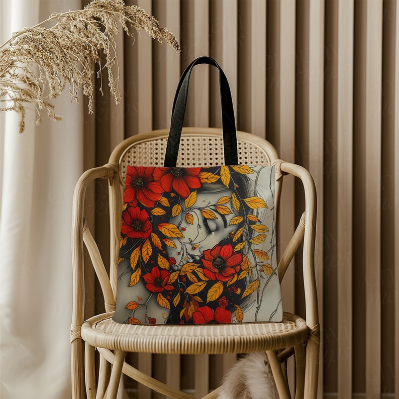May include: A tote bag with a colorful floral design featuring a woman's face partially obscured by the flowers. The flowers are red, orange, and yellow.