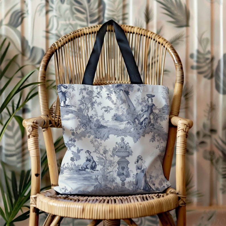 May include: A white tote bag with a black handle and a blue and white floral pattern. The bag features a repeating design of flowers, trees, and people in a garden setting.