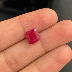 以下が含まれることがあります： 正方形の深い赤色のエメラルドカットの宝石です。