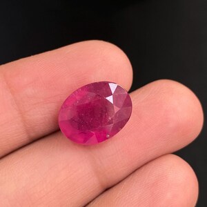 Puede incluir: Una gema ovalada de color rosa vibrante con un corte facetado.