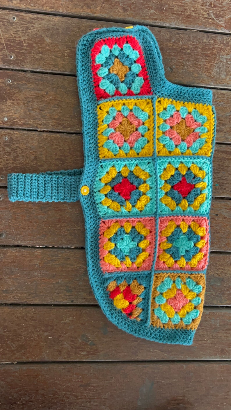 Pu&ograve; includere: Un giubbotto per cani in crochet blu turchese con una cinghia e una chiusura a bottone. Il giubbotto &egrave; realizzato con quadrati della nonna in tonalit&agrave; turchese, giallo, rosa e rosso.