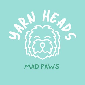 Pu&ograve; includere: Disegno a linea bianca di un muso di cane con il testo "YARN HEADS" in un arco bianco sopra il cane e "MAD PAWS" in verde sotto il cane su uno sfondo blu chiaro.