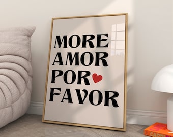 May include: A framed print with the text "More Amor Por Favor" in black with a red heart in the middle of the text. The print is on a cream background and is framed in a light wood frame.