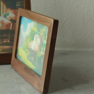 May include: A square wooden picture frame with rounded corners. The frame is made of a dark brown wood and holds a colourful image of a cartoon dog wearing sunglasses. Another frame is partially visible in the background.