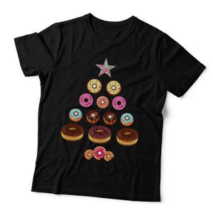 May include: A black t-shirt featuring a graphic print of various colourful doughnuts arranged in the shape of a Christmas tree, topped with a single multi-coloured star. The doughnuts include chocolate, pink, and blue frosted varieties.
