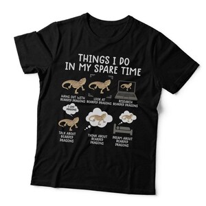 May include: A black short-sleeved t-shirt featuring the white text "THINGS I DO IN MY SPARE TIME" above six illustrations of bearded dragons. The graphics depict activities like hanging out, looking at, researching, talking about, thinking about, and dreaming about bearded dragons with corresponding labels.