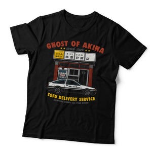 May include: A black t-shirt featuring a graphic print of a white and black car parked in front of a storefront. The text reads GHOST OF AKINA and son, TOFU DELIVERY SERVICE, and ACCEPTING ORDERS ALL YEAR ROUND, along with Japanese characters.