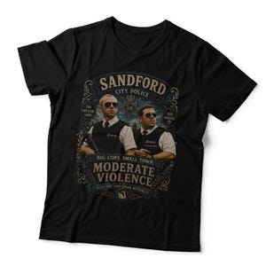 May include: A black short-sleeve t-shirt featuring a graphic print of two police officers in sunglasses and vests. The text reads Sandford City Police, The Greater Good, Our Specialty, Big Cops, Small Town, Moderate Violence, Just The One Swan Actually.