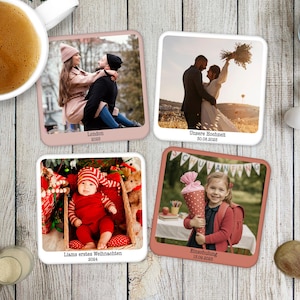 May include: Four square photo coasters with rounded corners, each displaying a different photograph. The images include a couple, a wedding, a baby, and a young girl. The coasters have a pink border and are arranged on a wooden surface.