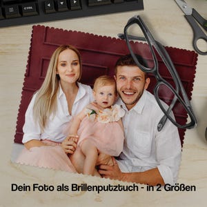Könnte beinhalten: Familienporträt auf einer weinroten Fotomatte, mit einer schwarzen Brille darauf. Der Text "Dein Foto als Brillenputztuch - in 2 Größen" ist unten sichtbar. Eine Tastatur, eine Schere und eine Computermaus sind ebenfalls im Bild.