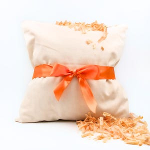 Zirbenkissen aus Bio-Baumwolle mit oranger Schleife – gefüllt mit duftenden Zirbenholzspänen. Natürliches Schlafkissen aus Zirbe, ideal als Geschenk und dekoratives Wohnaccessoire.