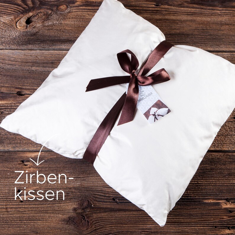 Ein Bio Zirbenkissen mit einer dekorativen Schleife und einem Hangtag. Die Füllung aus duftenden Zirbenholzspänen und der hochwertige Baumwollbezug machen es zu einem idealen Geschenk für erholsamen Schlaf.
