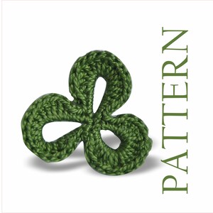Peut inclure: Un trèfle à trois feuilles vert crocheté à la main. Le trèfle est posé sur un fond blanc avec le mot "PATTERN" en texte vertical vert.