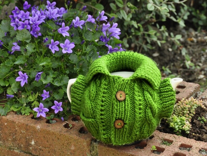 Jacket tea cozy with a pocket pattern, suitable for 4-6 cup pots about 1 liter volume. Six pages of detailed step-by-step instructions accompanied by pictures. Two small buttons added.