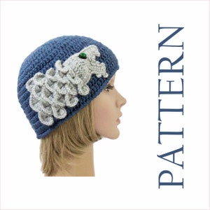 May include: A blue crocheted beanie with a gray crocheted dragon applique. The dragon has a green eye.