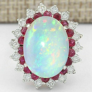 Può includere: Un anello con un opale bianco con un alone di diamanti e rubini. L'opale è di forma ovale e presenta un arcobaleno di colori.