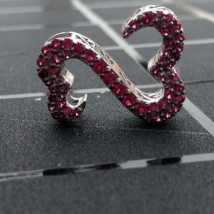 May include: A silver ring with a double heart design, set with pink gemstones.