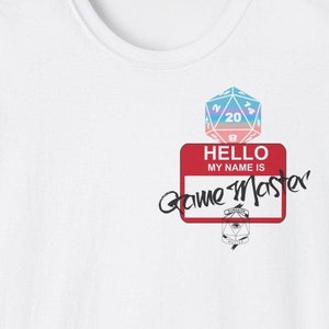 Può includere: Maglietta bianca con un dado a 20 facce colorato sopra un cartellino rosso con la scritta "HELLO MY NAME IS Game Master". Un piccolo logo di Dungeon Master è sotto il cartellino.