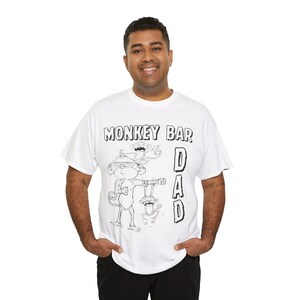 May include: White t-shirt with a black and white graphic of a monkey holding a drink and a smaller monkey hanging below. The text "MONKEY BAR DAD" is printed above and to the right of the monkey graphic.