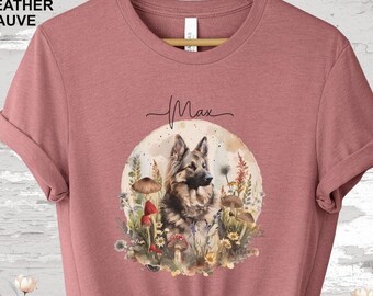 Puede incluir: Camiseta de color malva jaspeado con un gráfico de un perro pastor alemán en un entorno de bosque con setas y flores. El texto "Max" está impreso sobre el gráfico.