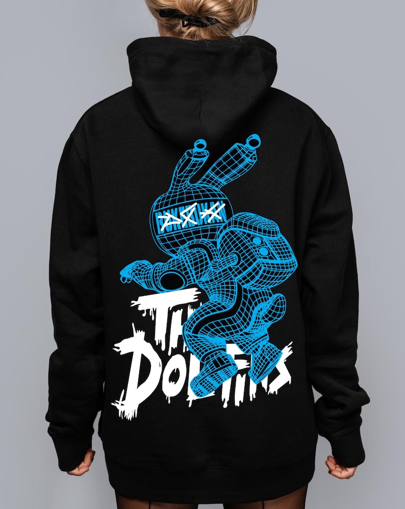 May include: A black hooded sweatshirt featuring a blue wireframe graphic of a rabbit-like character with X-shaped eyes. Below the character, the text "THE DOLLINS" is printed in a distressed white font. The design is centered on the back of the garment.