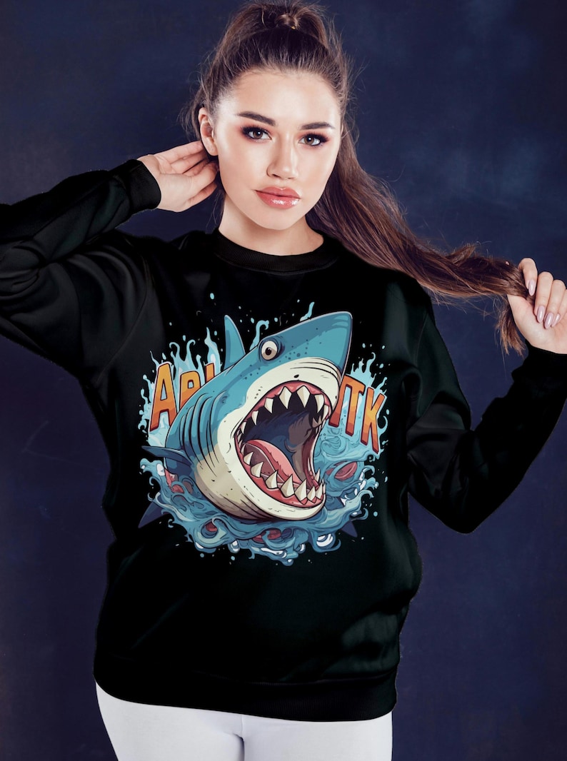 May include: Black sweatshirt with a graphic print of a blue shark with its mouth open, surrounded by water. The text "Акула" is printed on the sweatshirt.