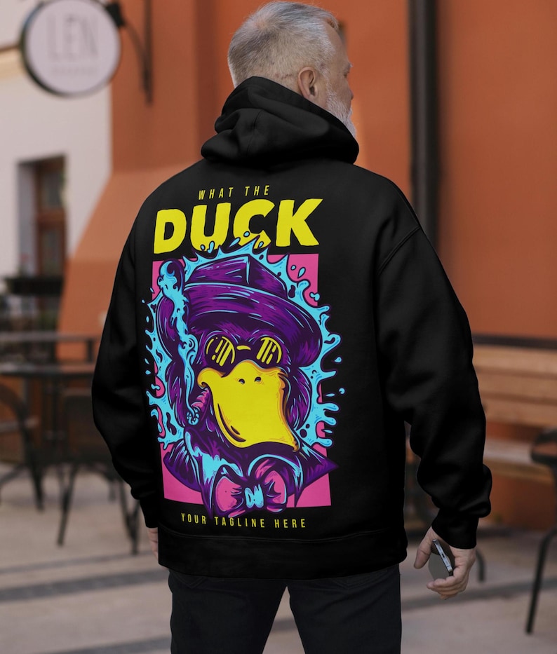 May include: A black hoodie featuring a graphic on the back with the text "WHAT THE DUCK" and "YOUR TAGLINE HERE". The design depicts a purple duck wearing a hat, sunglasses, and a bowtie, smoking a cigar, surrounded by blue splashes on a pink background.