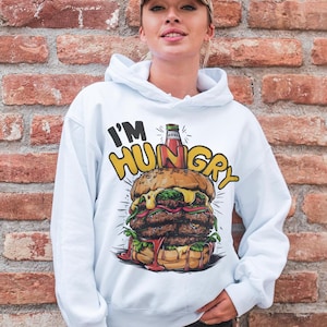 Pu&ograve; includere: Felpa bianca con una grafica di un grande hamburger con ketchup e il testo "I'm Hungry" stampato su di essa.