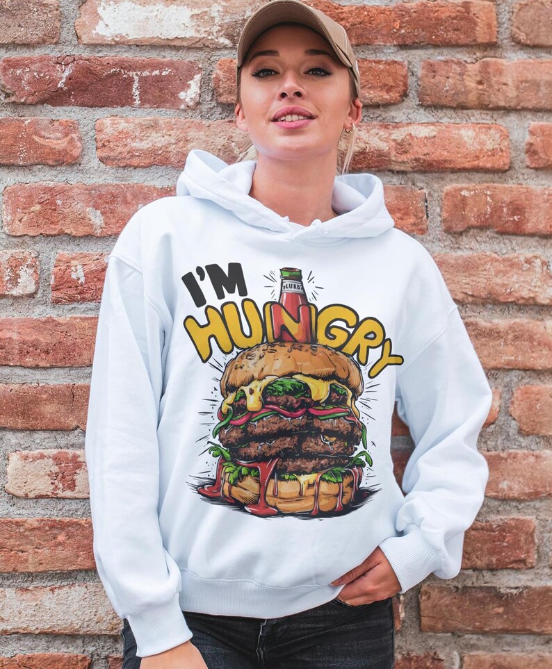Pu&ograve; includere: Felpa bianca con una grafica di un grande hamburger con ketchup e il testo "I'm Hungry" stampato su di essa.