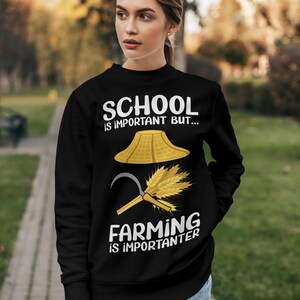 Pu&ograve; includere: Felpa nera con la scritta "SCHOOL is important BUT... FARMING is importanter." Il design include un cappello di paglia, un falcetto e del grano. La felpa &egrave; indossata da una persona.