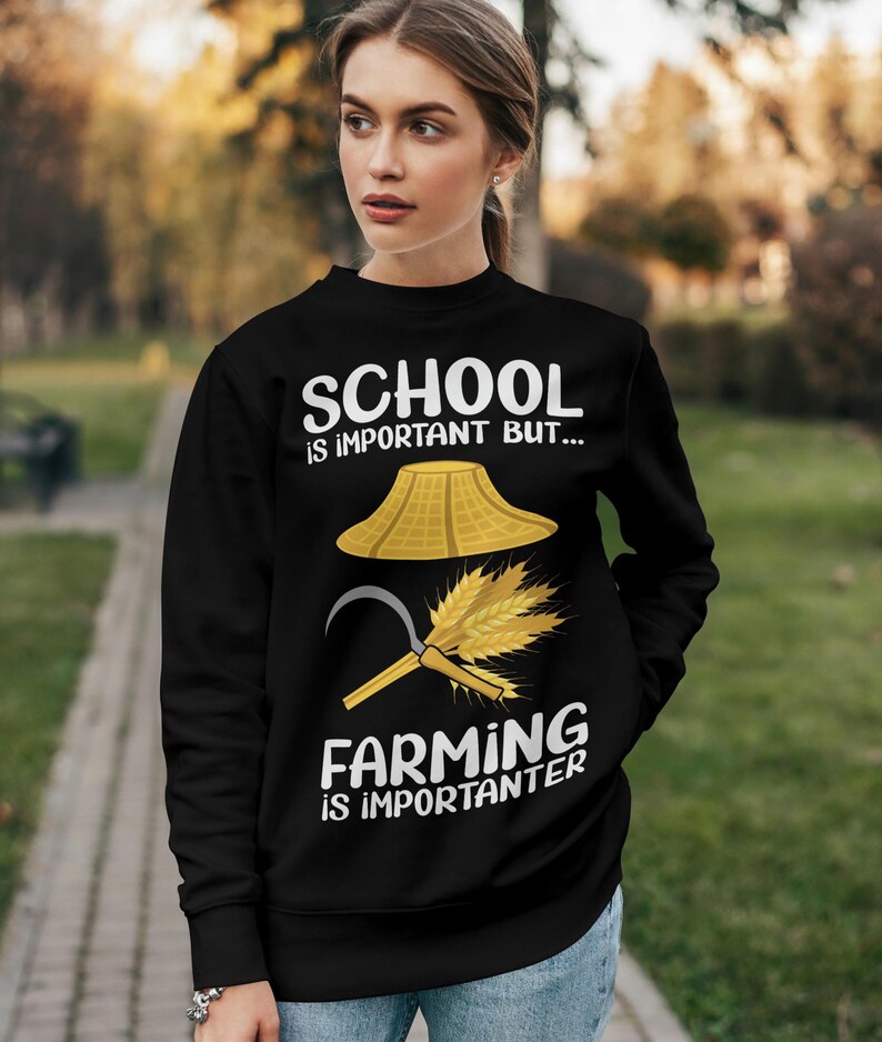 Pu&ograve; includere: Felpa nera con la scritta "SCHOOL is important BUT... FARMING is importanter." Il design include un cappello di paglia, un falcetto e del grano. La felpa &egrave; indossata da una persona.