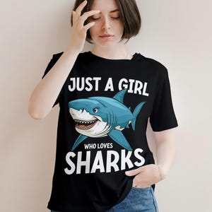 May include: Black t-shirt with a white graphic of a shark and the text "Just a girl who loves sharks".