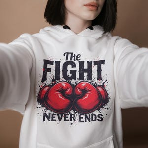 Peut inclure: Sweat-shirt blanc avec un imprim&eacute; graphique de gants de boxe et le texte "The Fight Never Ends".