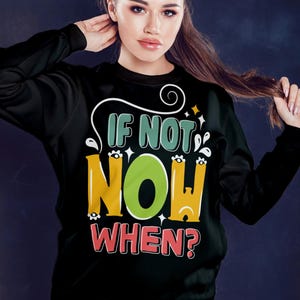 May include: Black sweatshirt with the text "IF NOT NOW WHEN?" in a colorful, playful font. The word "NOW" is in a large, bright green circle. The design includes white swirls and star accents.