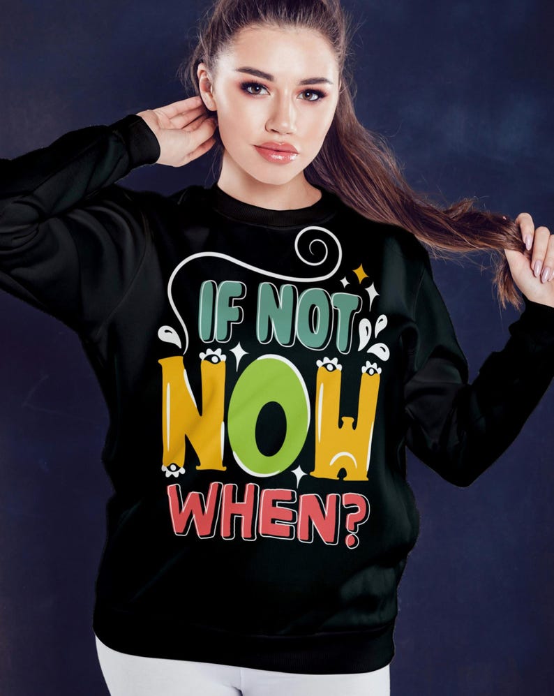 May include: Black sweatshirt with the text "IF NOT NOW WHEN?" in a colorful, playful font. The word "NOW" is in a large, bright green circle. The design includes white swirls and star accents.